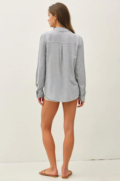 Woman wearing a light gray button-up shirt and shorts on a white background