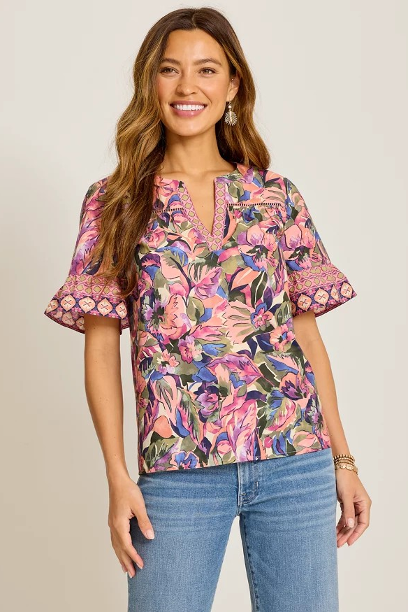 Woman wearing a colorful floral blouse with short sleeves on a plain background