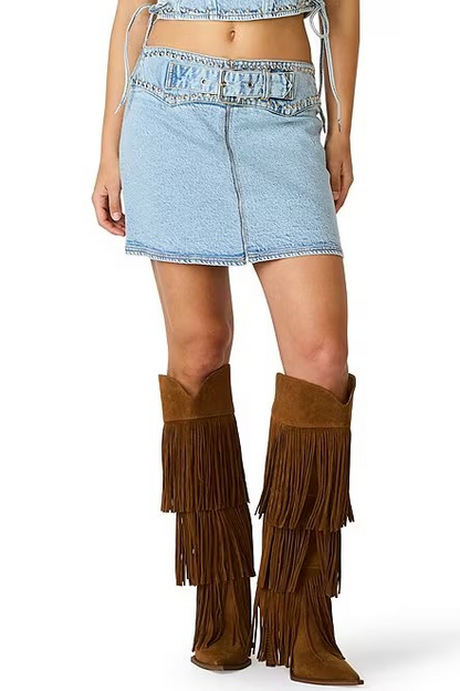 Person wearing denim shorts and brown fringed boots on a white background