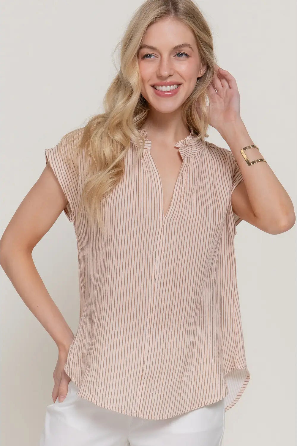 Woman wearing a beige striped blouse against a white background