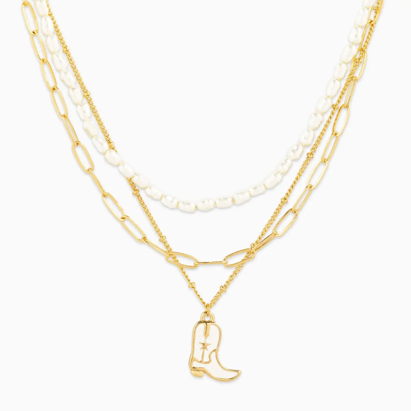 Layered gold and pearl necklaces with a cowboy boot charm on a white background