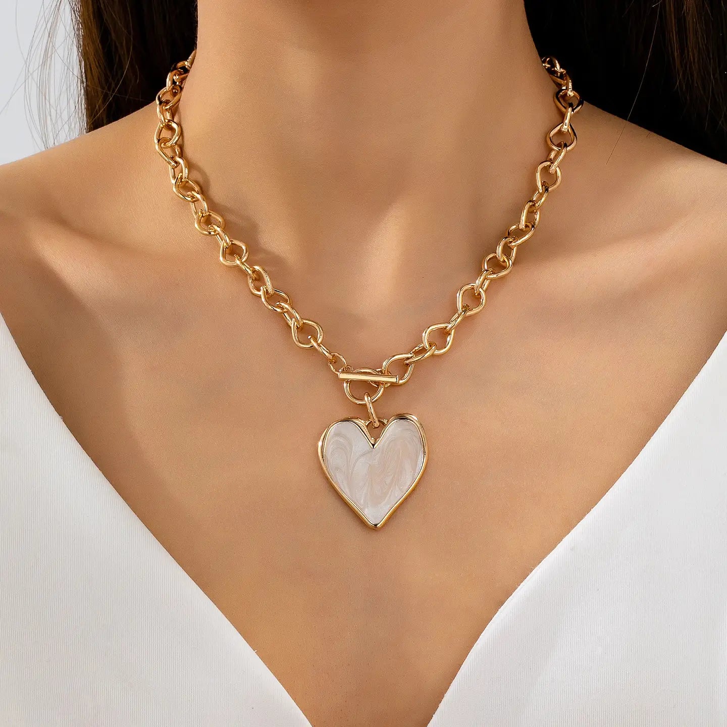 Gold chain necklace with a heart-shaped pendant on a mannequin.