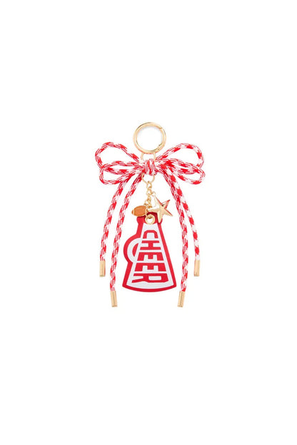 A red and white braided bow charm with a gold-tone ring, dangling red and white braided cords, a small gold star, and a red and white braided bottle charm featuring a gold Chinese double happiness symbol.