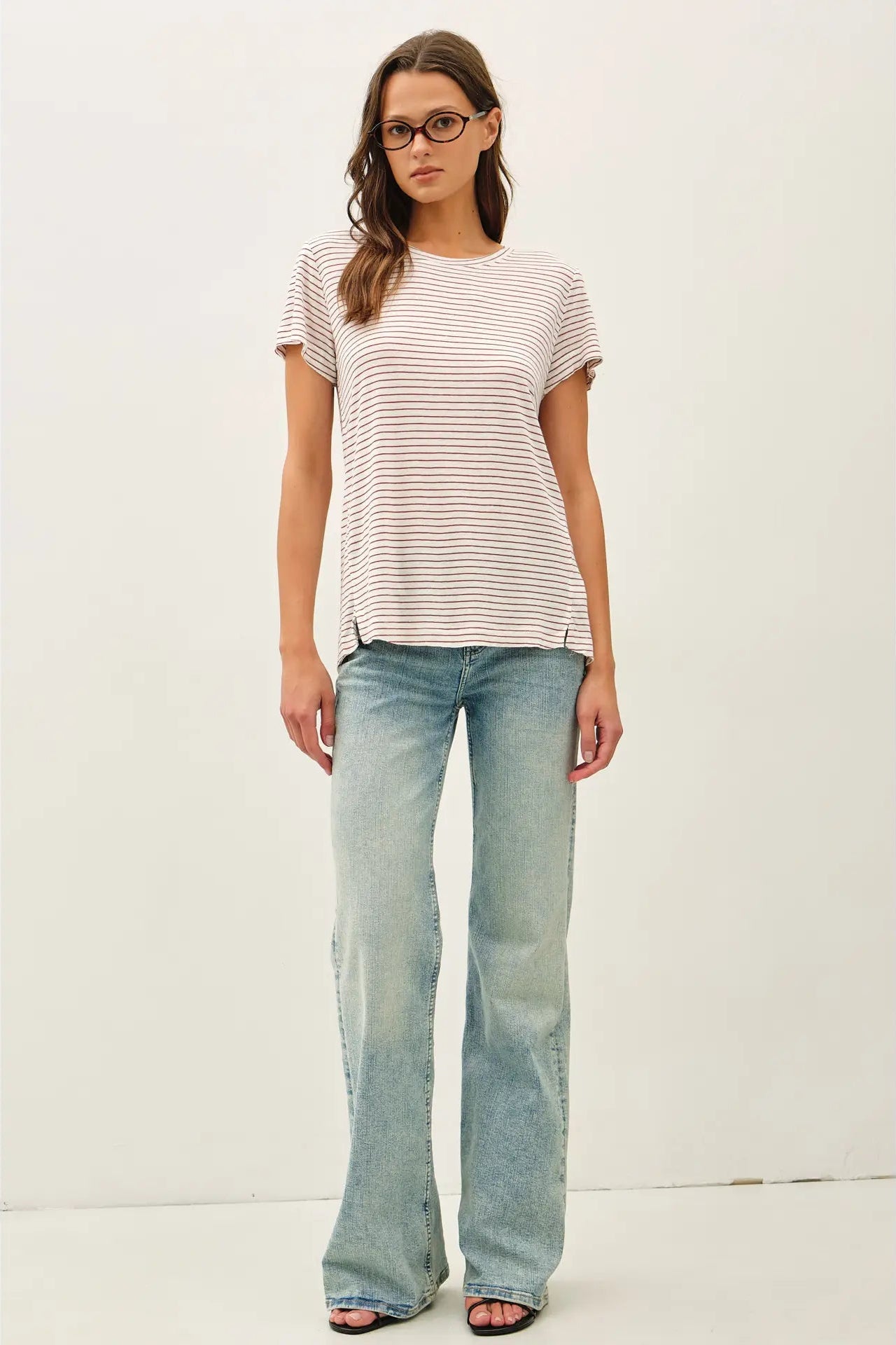 Woman wearing a striped shirt and light blue jeans on a white background