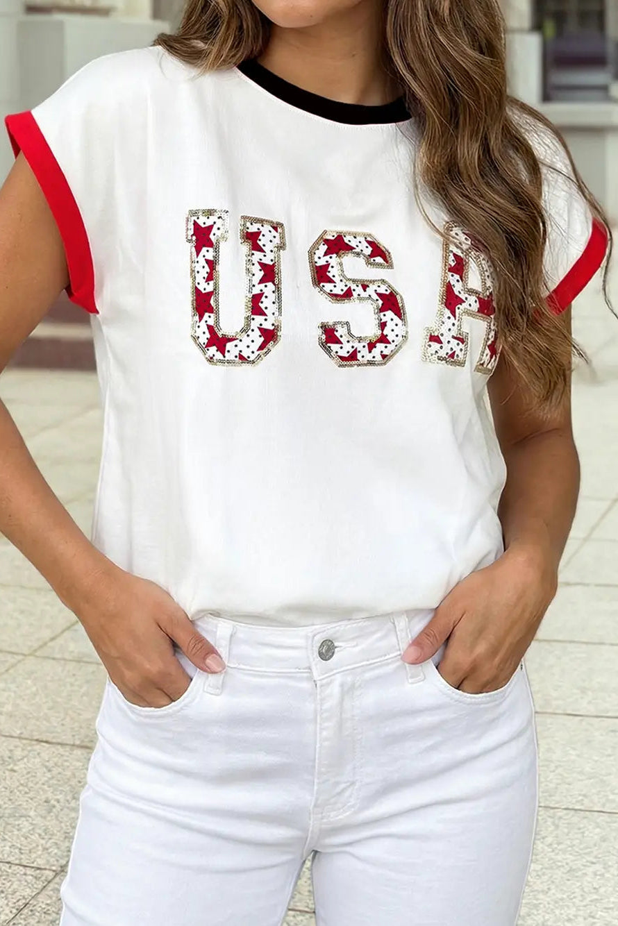 Person wearing a white t-shirt with 'USA' in red sequins and white pants.