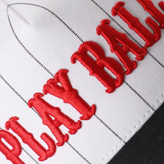 Close-up of a white baseball cap with red 'Play Ball!' text on a black background