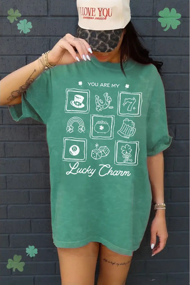 Person wearing a green t-shirt with 'Lucky Charm' design against a brick wall.