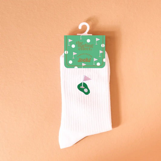 White sock with golf-themed design on a hanger against an orange background