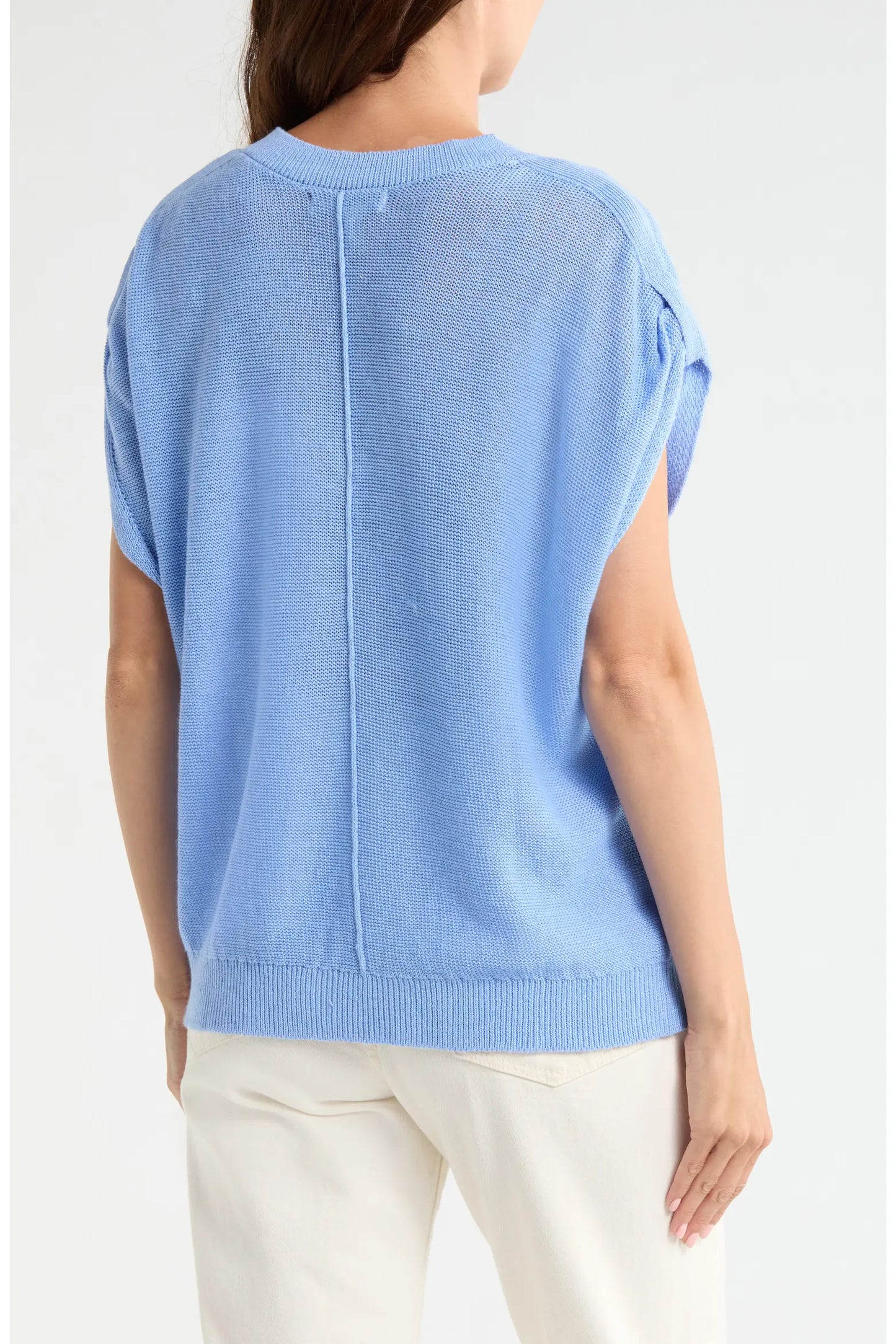 Light blue sleeveless sweater worn by a person on a white background