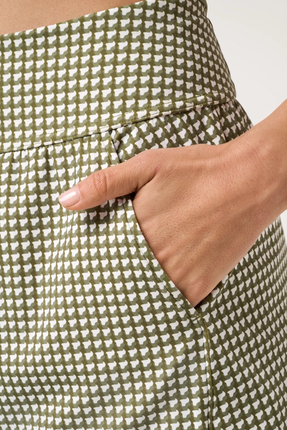 Green and white checkered skirt with a hand in the pocket against a neutral background