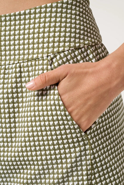 Green and white checkered skirt with a hand in the pocket against a neutral background