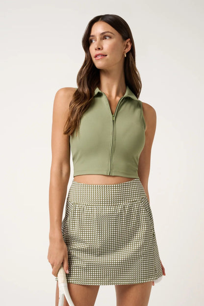Woman wearing a green sleeveless top and checkered skirt on a white background