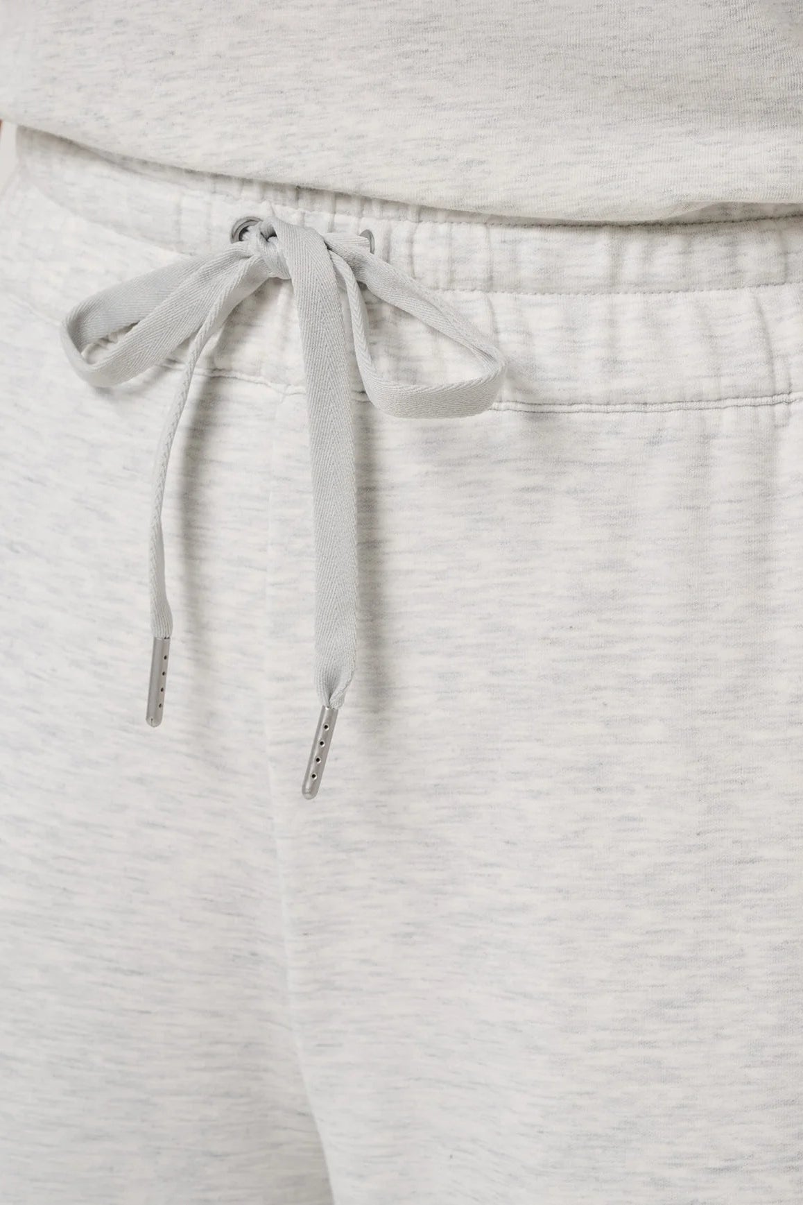 Close-up of light heather gray sweatpants showing the drawstring waistband and part of a matching top.