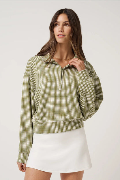 Woman wearing a green checkered shirt and white skirt on a light gray background
