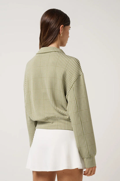 Woman wearing a green checkered shirt and white skirt on a plain background