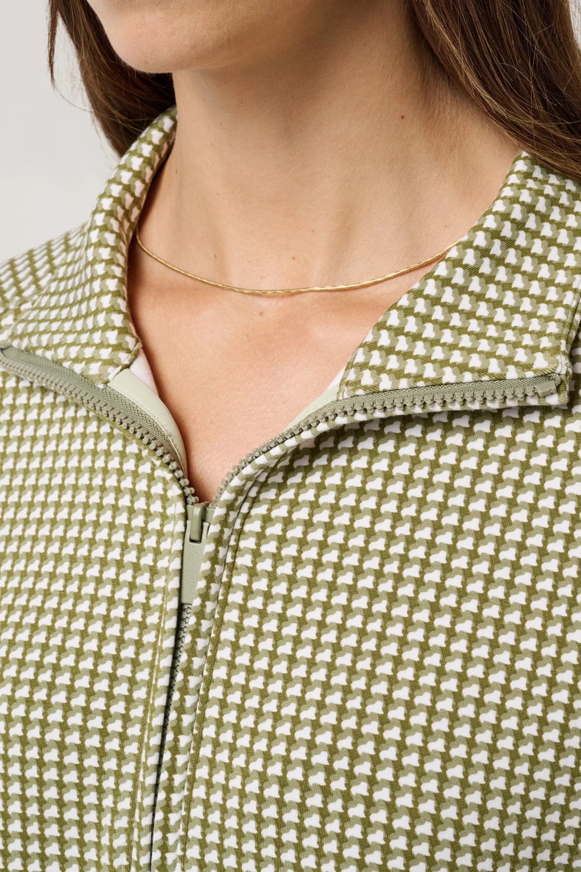 Close-up of a person wearing a green and white patterned jacket with a zipper.