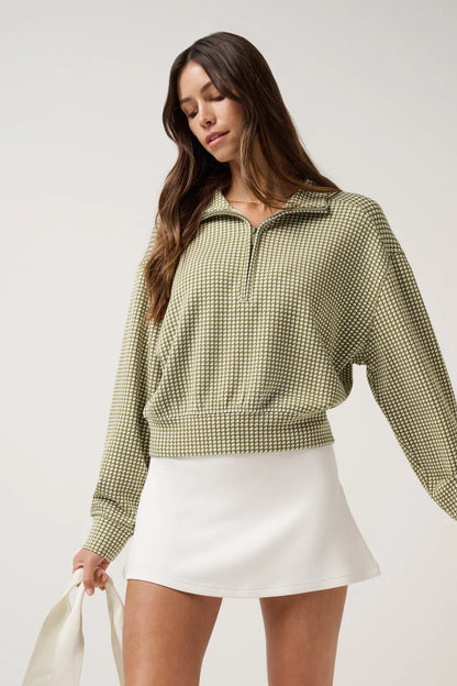Woman wearing a green checkered shirt and white skirt on a light background