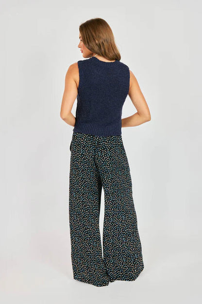 Woman wearing a navy sleeveless top and patterned pants on a light gray background