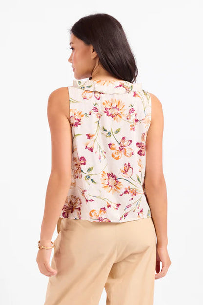 Woman wearing a sleeveless floral top and beige pants on a white background