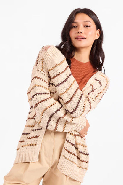 Woman wearing a beige cardigan with brown stripes on a white background