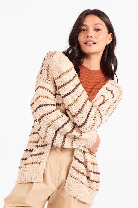 Woman wearing a beige cardigan with brown stripes on a white background