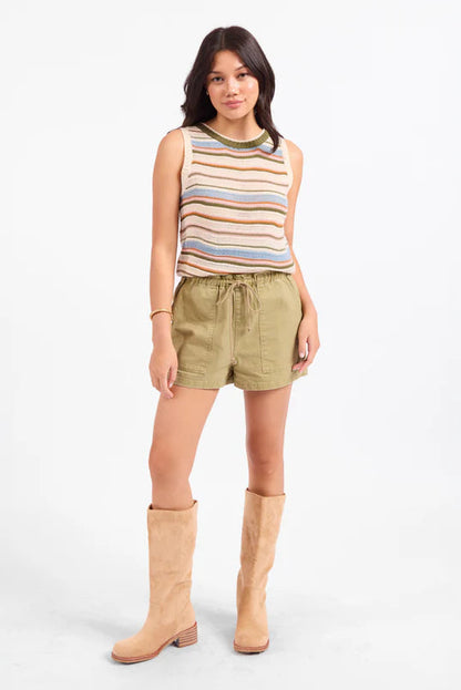 Woman wearing a striped tank top and shorts with tan knee-high boots on a white background