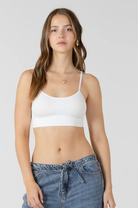 Woman wearing a white crop top and blue jeans on a plain background