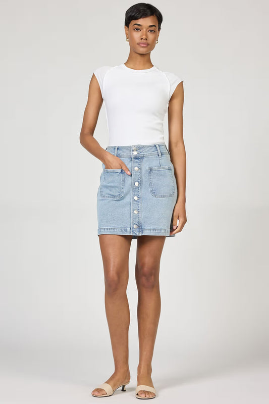 Woman wearing a white sleeveless top and light blue denim skirt on a plain background