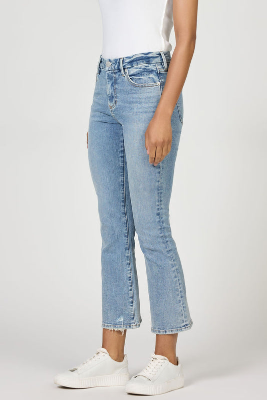 Person wearing light blue jeans and white sneakers on a white background