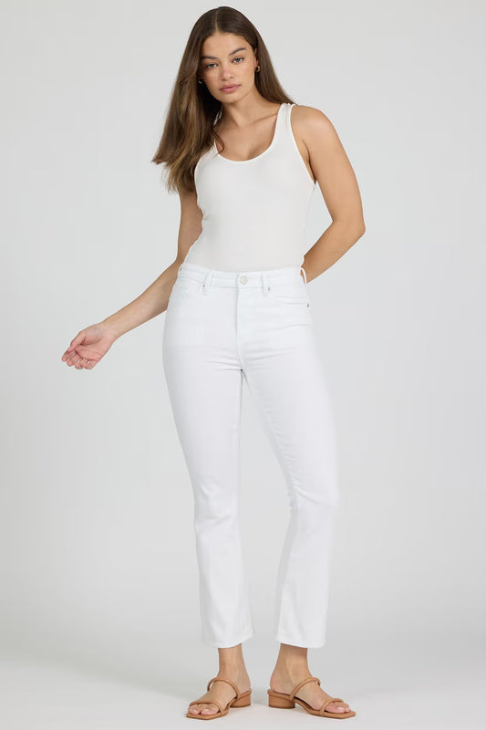 Woman wearing a white sleeveless top and white pants on a plain background