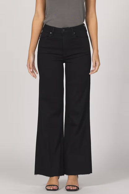 Person wearing black wide-leg jeans on a plain background