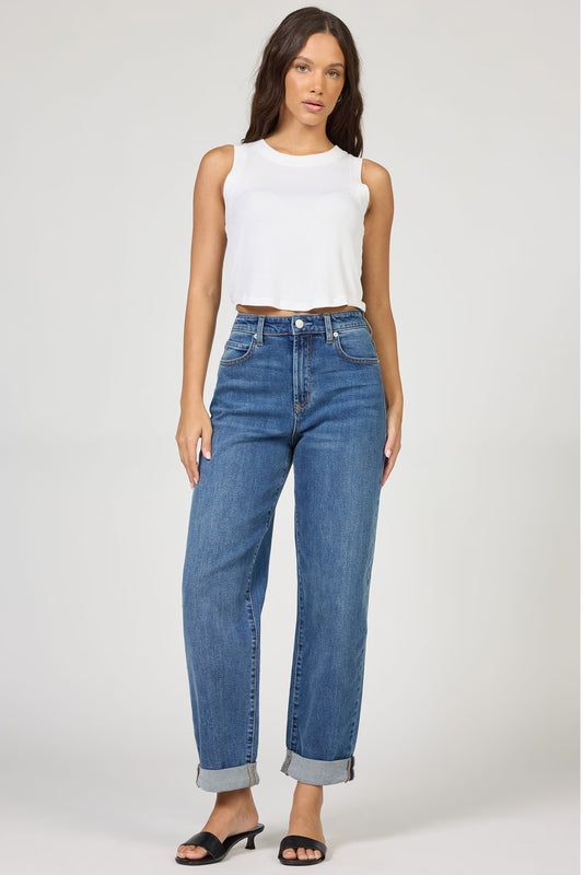 Woman wearing a white sleeveless top and blue jeans on a white background