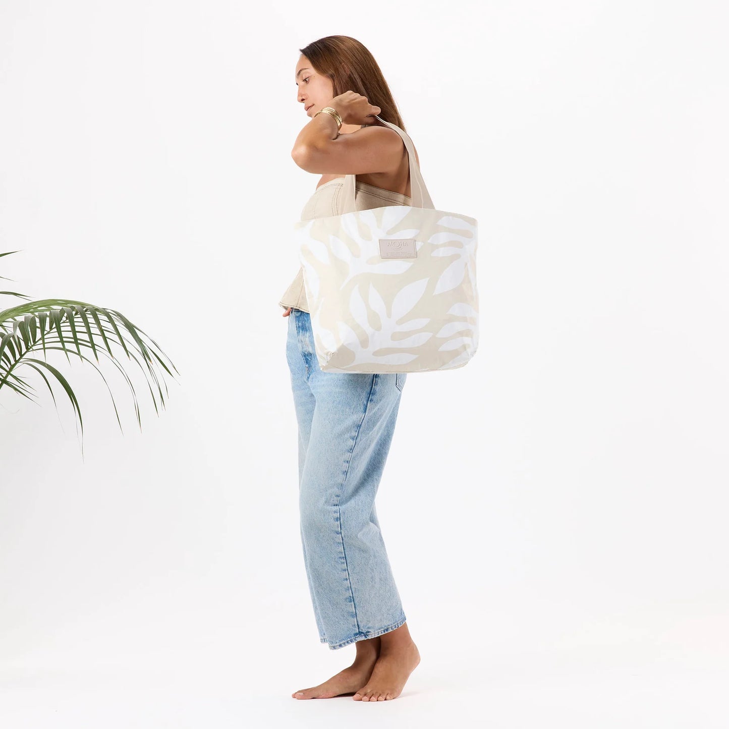 Woman holding a large white tote bag with a pattern against a white background