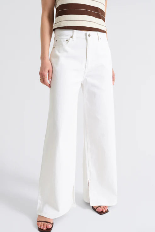 Person wearing a striped top and white wide-leg pants on a plain background