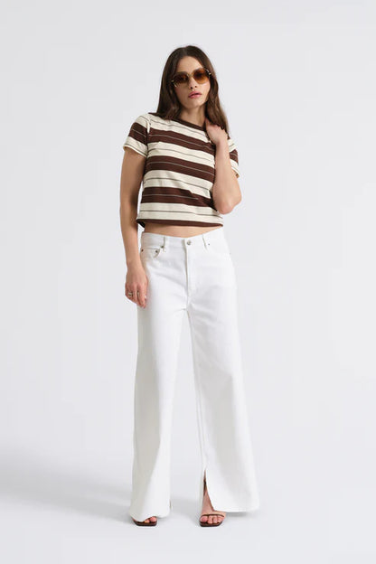 Woman wearing a striped crop top and white pants on a white background