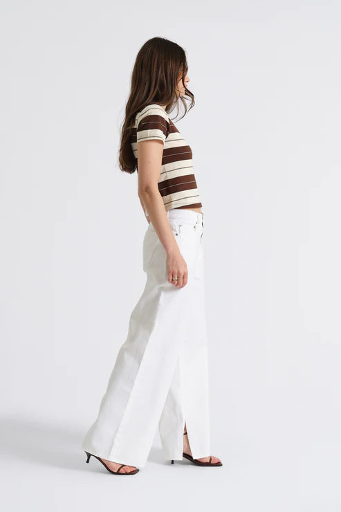 Woman wearing a striped shirt and white pants on a plain background