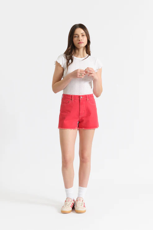 woman wearing coral colored cut off shorts with white top 