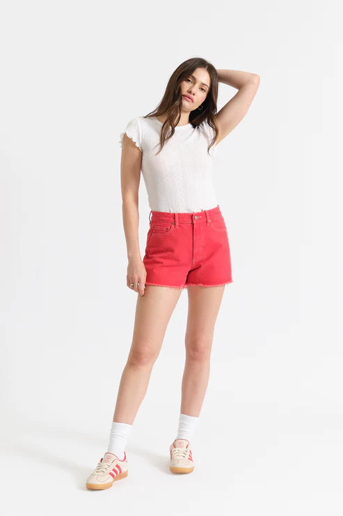 woman wearing coral colored cut off shorts with white top 