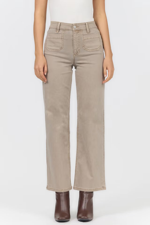 A model wearing a pair of light beige straight-leg jeans with brown ankle boots, shown from the waist down against a plain white studio background.