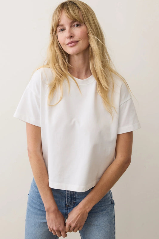 Woman wearing a white t-shirt and blue jeans against a plain background