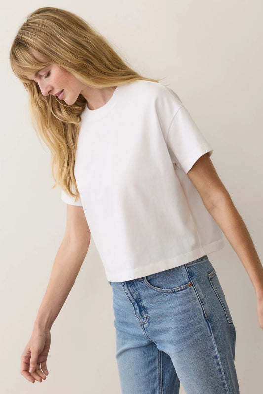 Woman wearing a white t-shirt and blue jeans against a plain background