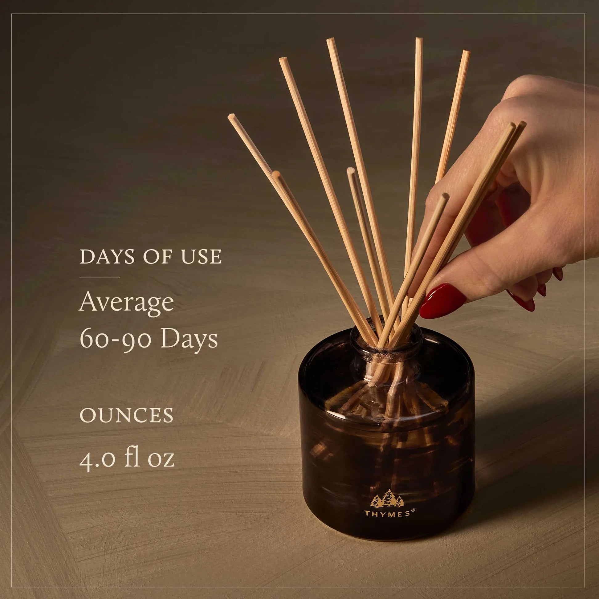 Hand holding a diffuser with reeds, showing product details on a brown background