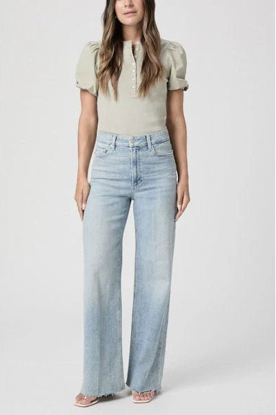 Woman wearing a light-colored top and high-waisted jeans on a white background