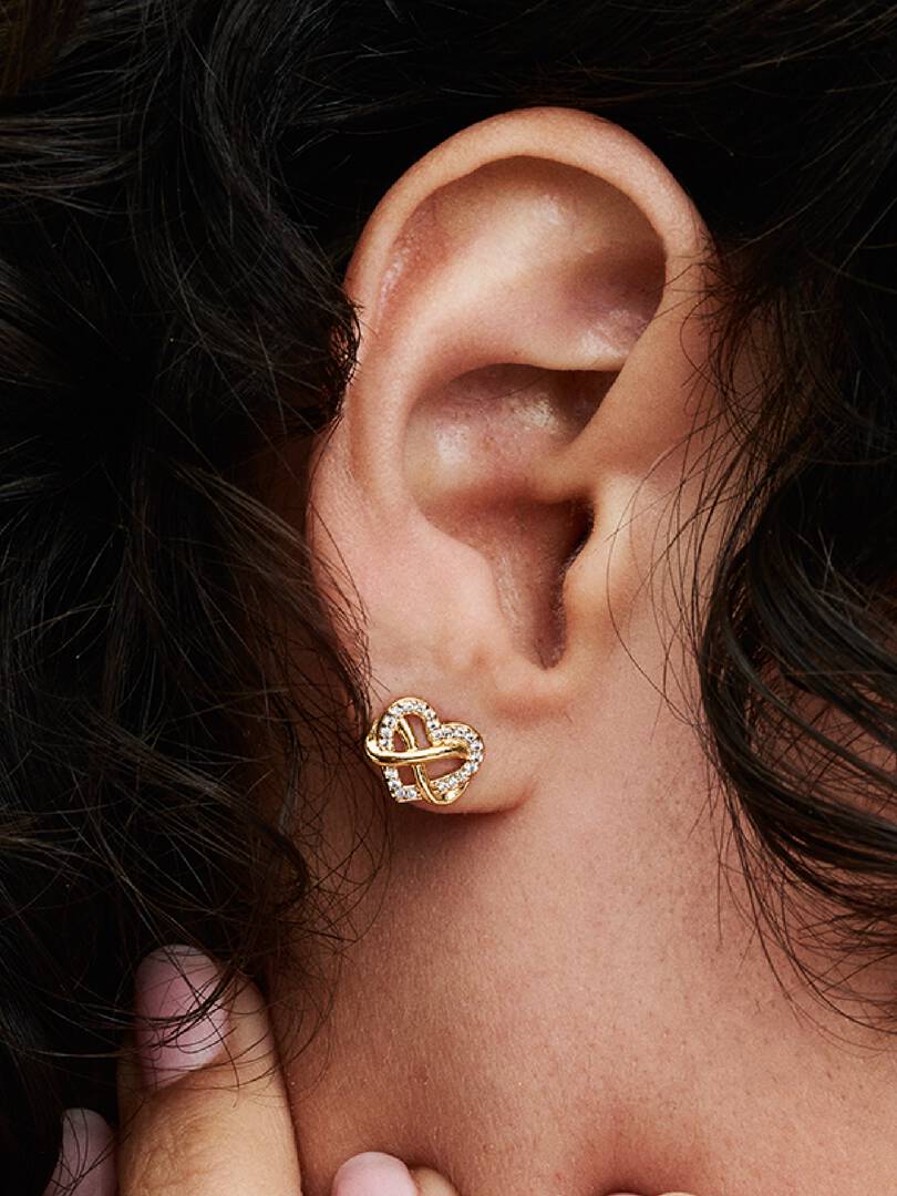 Close-up of an ear wearing a gold earring with interlocking design.