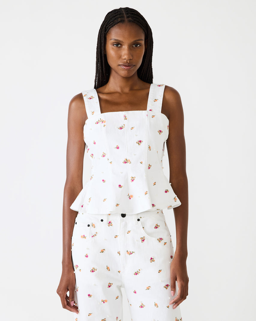 Woman wearing a white floral sleeveless top and pants on a white background