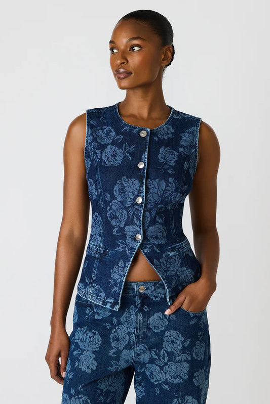 Woman wearing a blue floral sleeveless top and pants on a white background