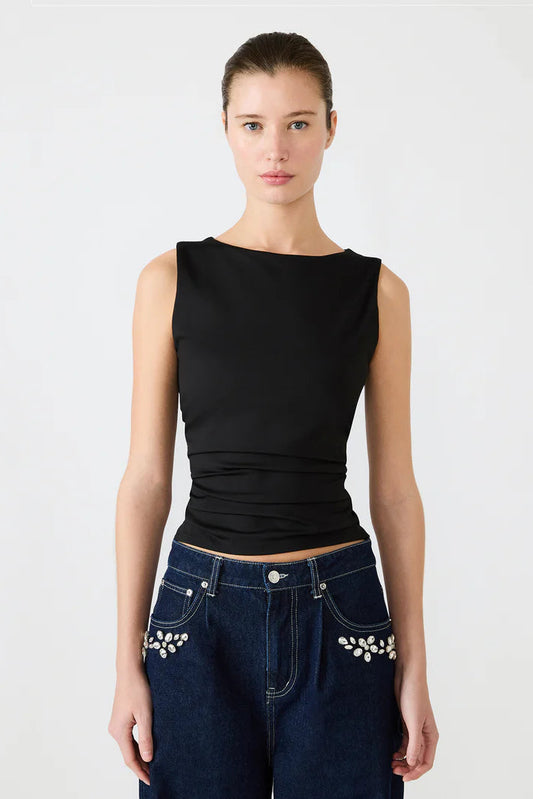 Woman wearing a black sleeveless top and blue jeans with decorative elements on a white background