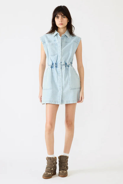 Woman wearing a light blue denim dress with brown boots on a white background