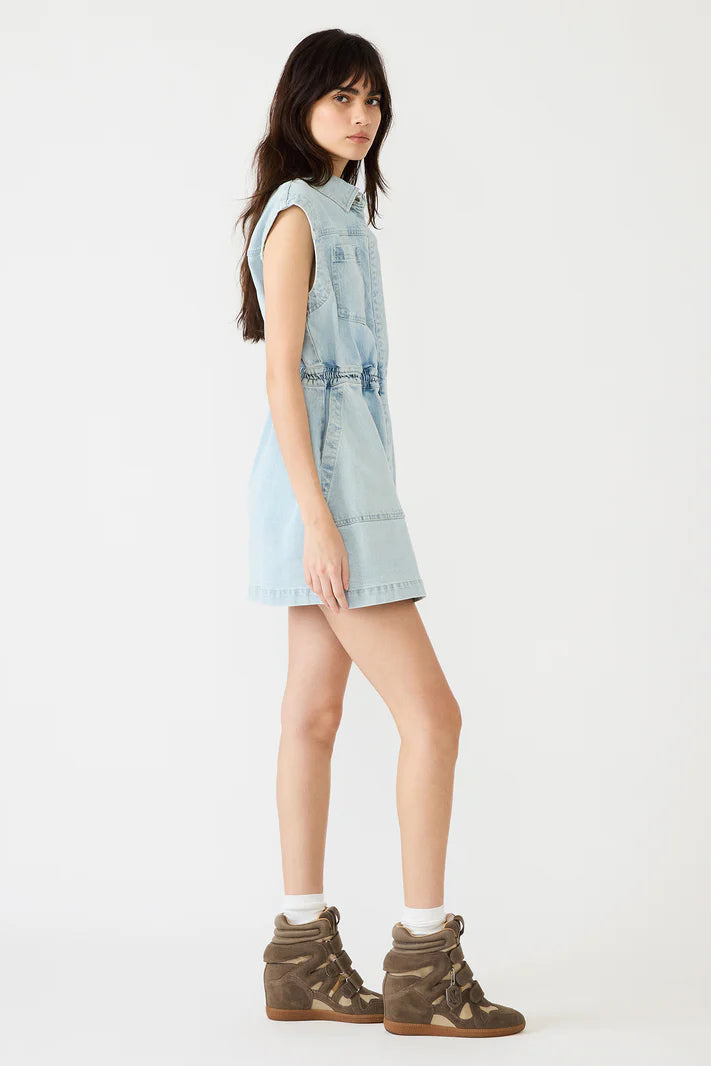 Woman wearing a light blue denim dress with brown boots on a white background
