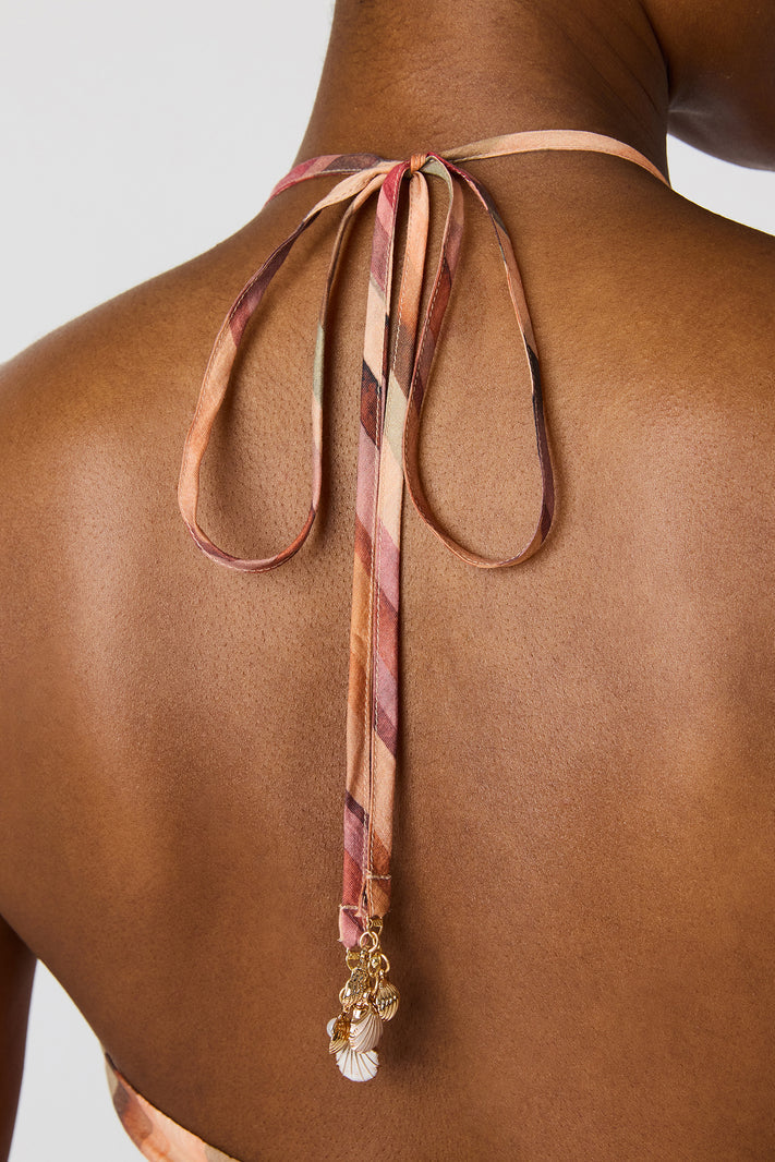 Strapless top with a decorative ribbon and beads on a plain background